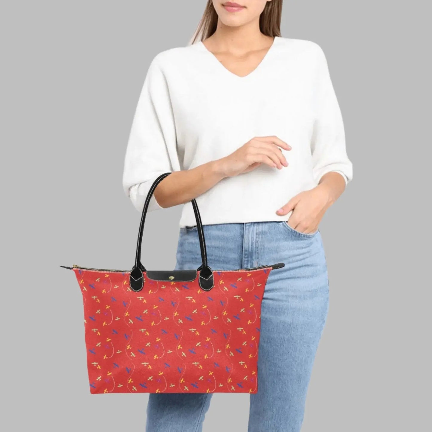 red handbag with rolled straps and airplane pattern