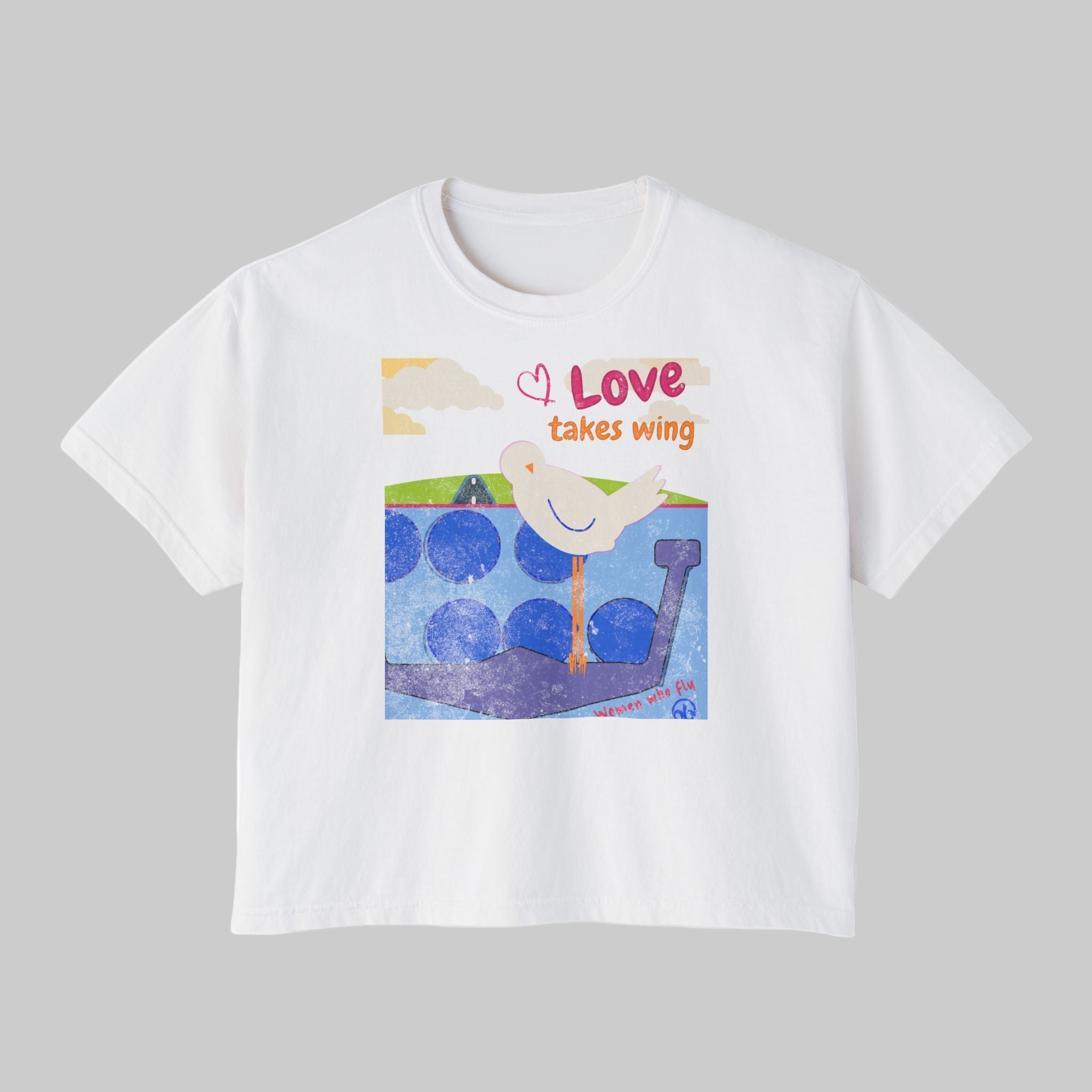 White t-shirt with a colorful graphic of a dove and text 'Love takes wing' on a white background