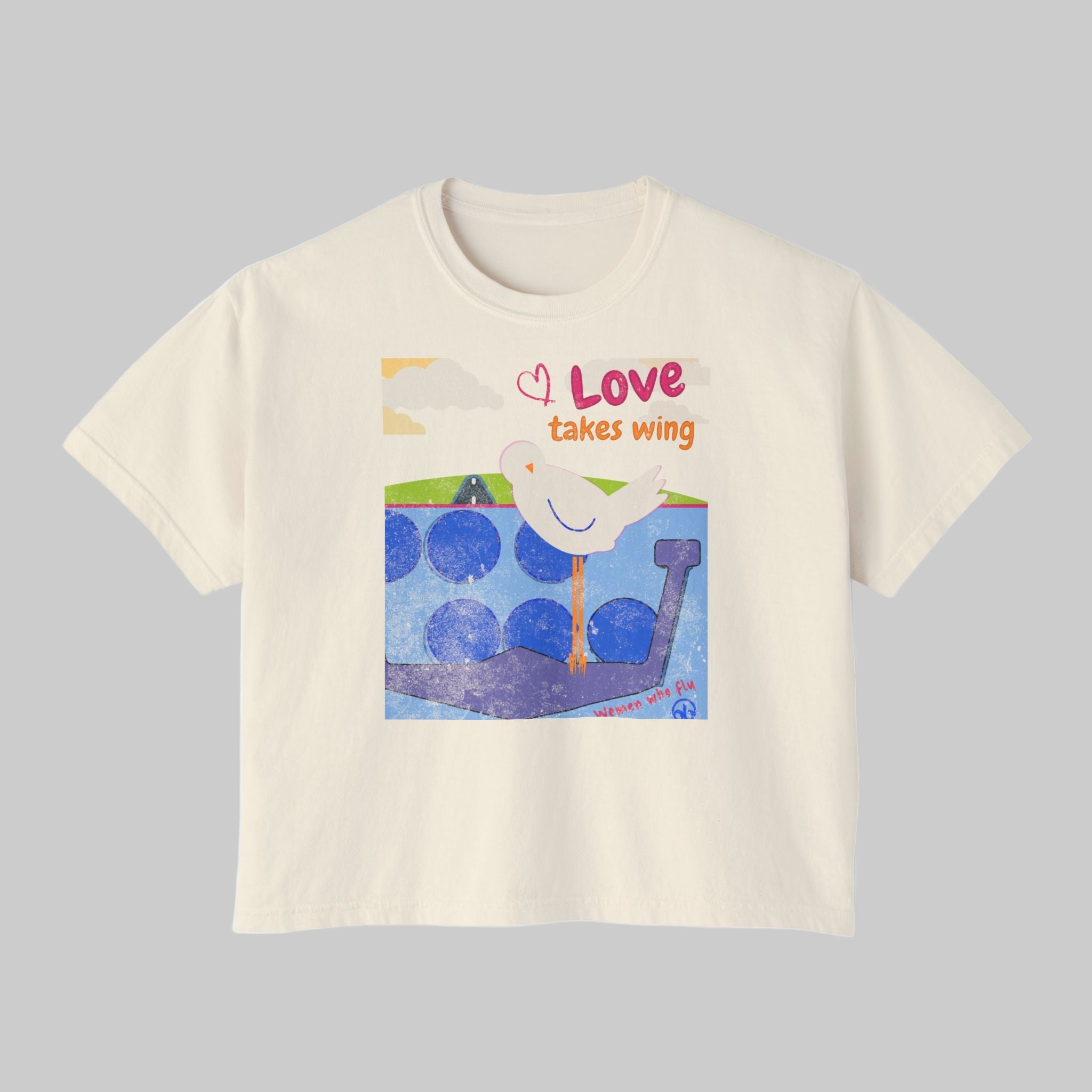 Beige t-shirt with a graphic of a dove and text 'Love takes wing' on a white background