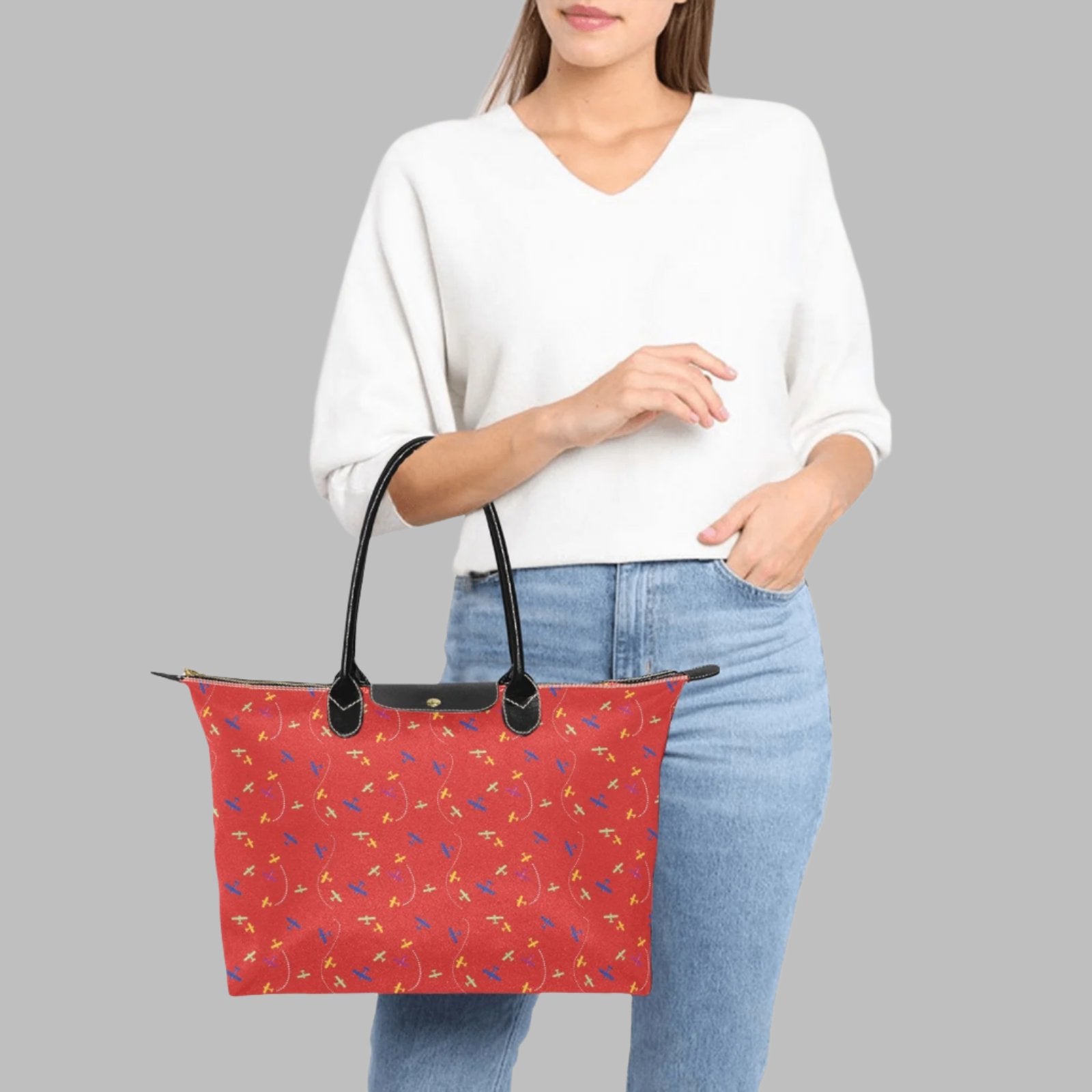 red handbag with rolled straps and airplane pattern 